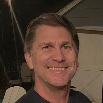 Patrick Noble, smiling, outdoors in the evening
